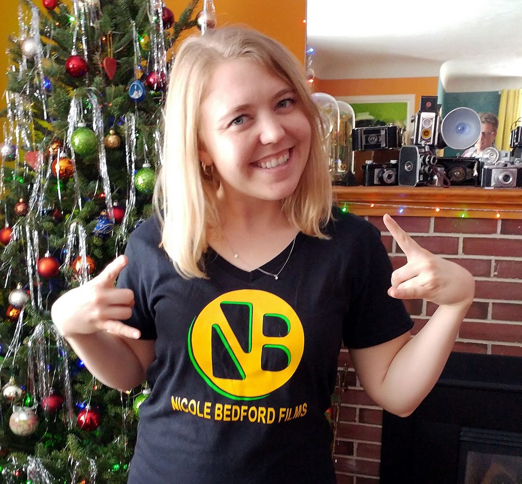 Nicole Bedford wearing a Tshirt with her "Nicole Bedford Films" logo (an N & B in a circle, reminiscent of a film reel) on the front.